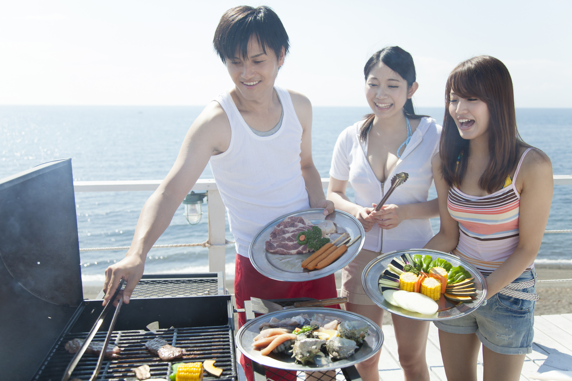 海辺でBBQをする3人