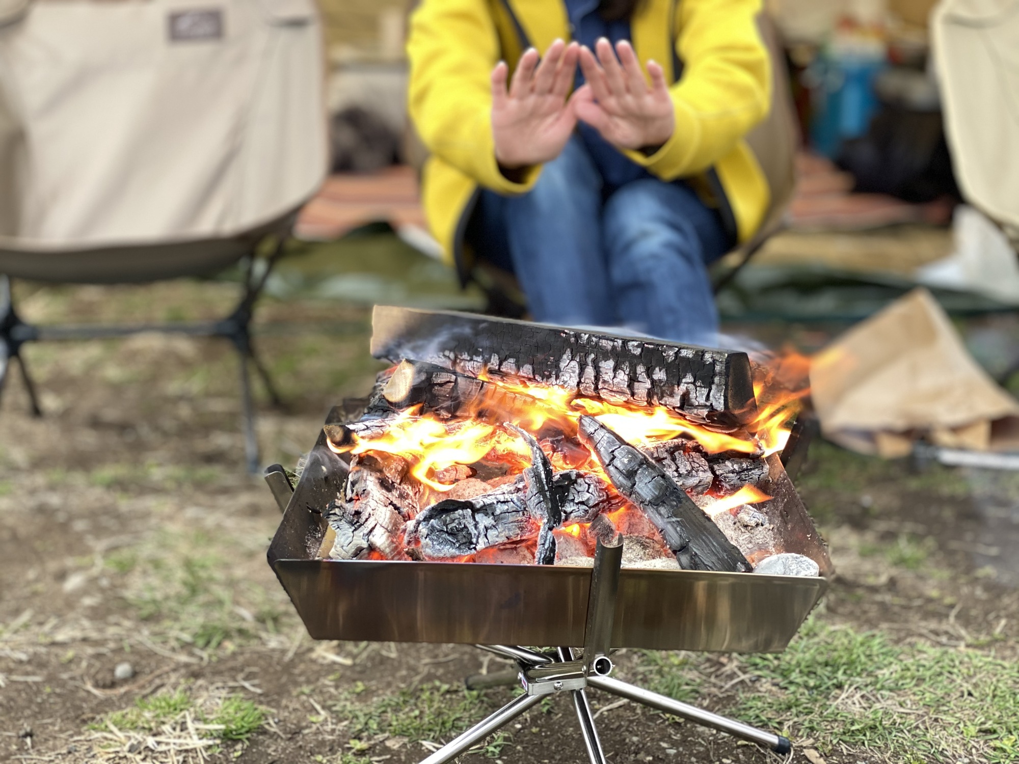 キャンプで焚火にあたる女性